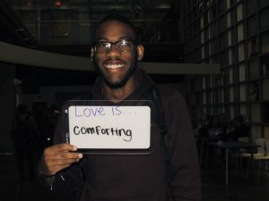 Student holding a sign that says “Love is comforting”