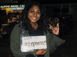 Student holding a doughnut and a sign that says “love is acceptance”
