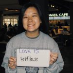 Student holding a sign that says “love is selfless”
