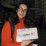 Student holding a sign that says “love is support”