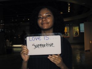 Student holding a sign that says “love is supportive”