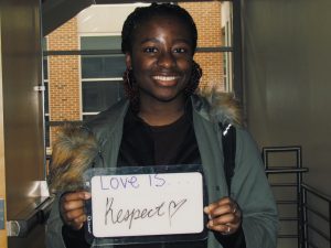 Student holding a sign that says “love is respect”