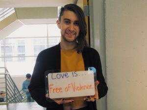 student holding a sign that says “love is free of violence”