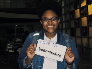 Student holding sign that says “Love is understanding”