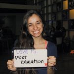 Student holding a sign that says “Love is peer education”