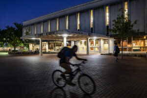 A cyclist passing by the library at nightime